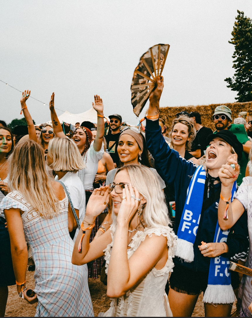 Festival crowd dancing with woman holding hand fan high in the air