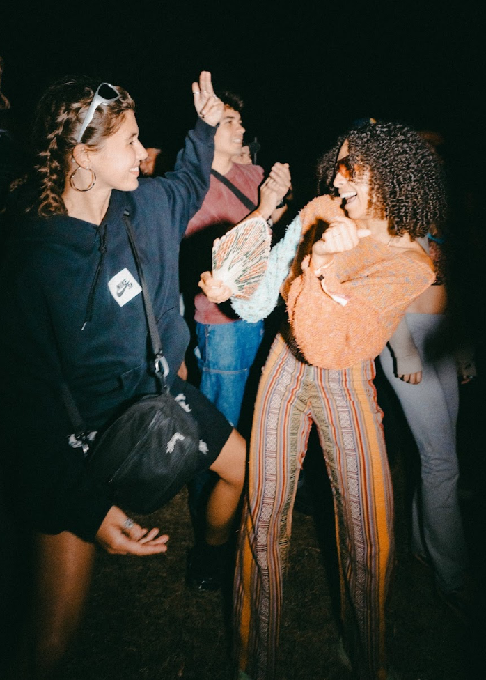 Friends dancing at a festival at night, one holding a hand fan